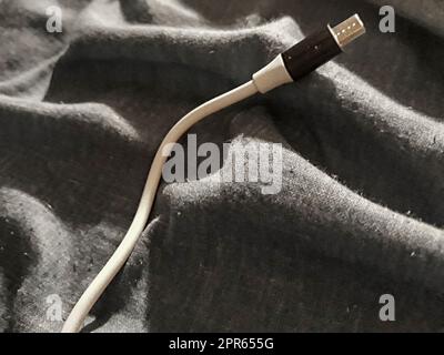 Top view shot smartphone cable over unattended bed blanket Stock Photo