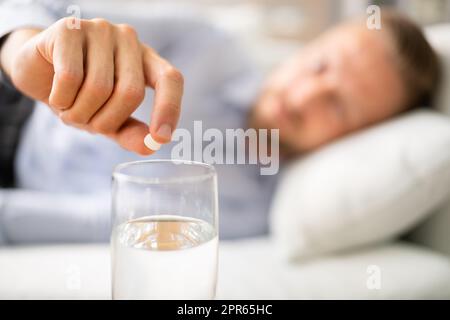 Man With Hangover Taking Medicine Pill Stock Photo