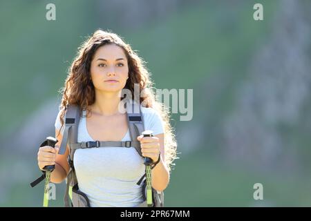 Hiker walking in the mountain wih poles and backpack Stock Photo