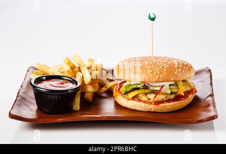 Burger. Juicy pork cutlet, cheddar cheese, crispy pickled onions, lettuce wrapped in a bun under two sauces. Served with french fries Stock Photo