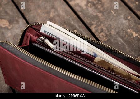 Leather red wallet with money and credit cards on old wooden background Stock Photo