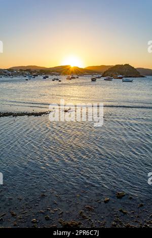 Sunset behind the hills and reflected in the sea waters in Buzios Stock Photo