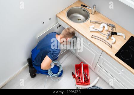 Plumber Cleaning Clogged Sink Pipe Stock Photo