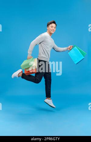 Full length profile photo of handsome man carry bags jump high isolated blue color background Stock Photo