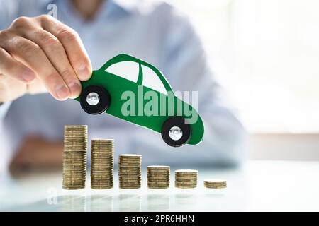 Person Flying Car Over Declining Stacked Coins Stock Photo