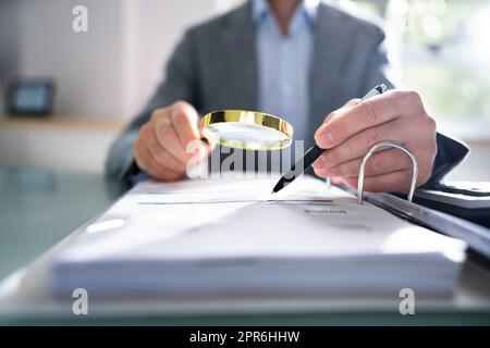 Businessperson Looking At Receipts Through Magnifying Glass Stock Photo