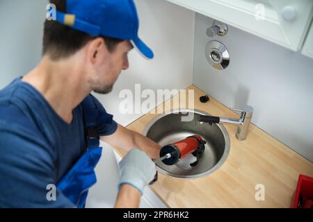 Plumber Cleaning Drain And Sink Stock Photo