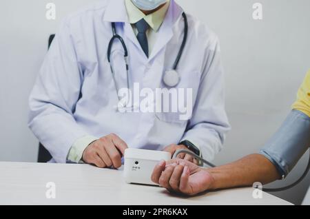 doctor measures the blood pressure of an elderly male patient. Stock Photo