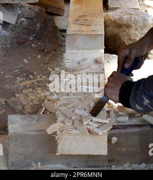 Carpenter working with a chisel in a wooden beam Stock Photo