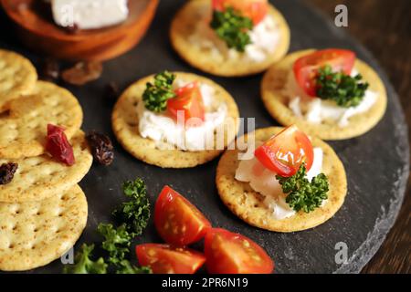 Appetizers and snacks, crackers, dried fruit, tomatoes, parsley, and cream cheese Stock Photo