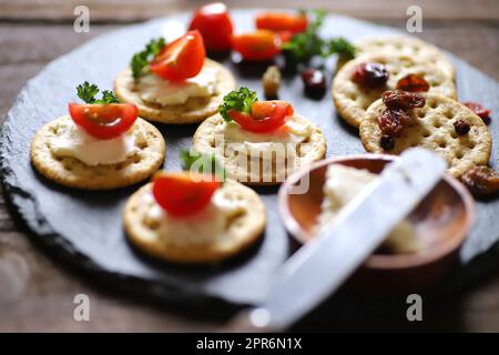 Appetizers and snacks, crackers, dried fruit, tomatoes, parsley, and cream cheese Stock Photo