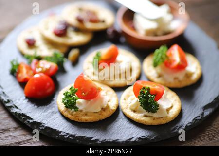 Appetizers and snacks, crackers, dried fruit, tomatoes, parsley, and cream cheese Stock Photo