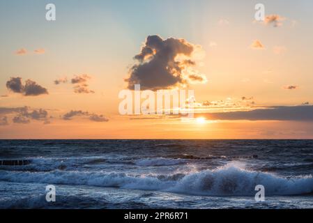 colored sunset with cloud cover over the sunset at the beach - dramatic sunset on the baltic sea Stock Photo
