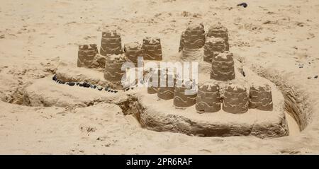 A sandcastle, blob castle built on a beach with childrens toys. Stock Photo