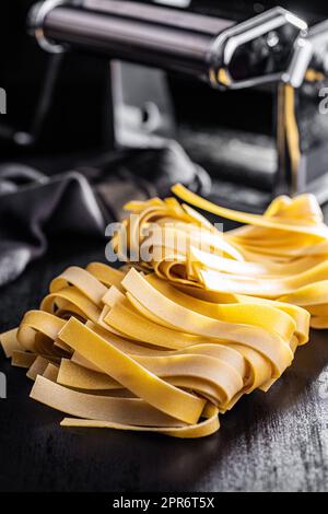 Uncooked pappardelle pasta on black table. Stock Photo