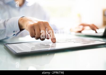 Businessperson Analyzing Invoice On Digital Tablet Stock Photo