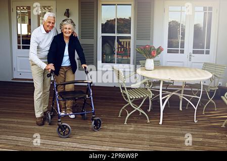 Theyll always support each other. Portrait of a smiling senior woman using a walker with her husband beside her outside their home. Stock Photo