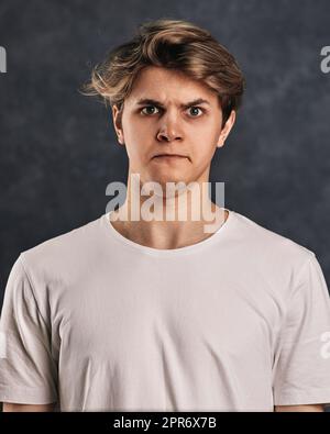 handsome guy grimacing on a dark gray background Stock Photo