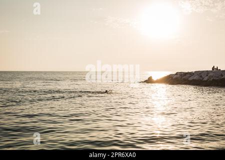 Colorful ocean beach sunrise with deep blue sky and sun rays Stock Photo