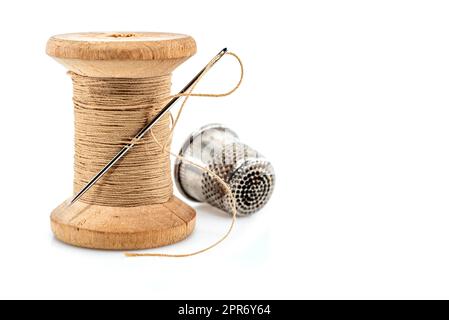 Vintage wooden spool of black thread and needle on white