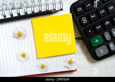 Sticky Note With Important Message Over Notebook With Pencil And Flowers On Desk With Calculator. Memo With Crutial Information Over Notepad On Table. Stock Photo