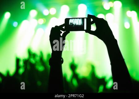 A person filming their favorite band with a camera phone. This concert was created for the sole purpose of this photo shoot, featuring 300 models and 3 live bands. All people in this shoot are model released. Stock Photo
