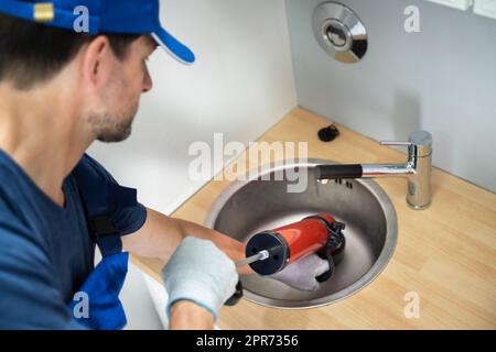 Plumber Cleaning Drain And Sink Stock Photo