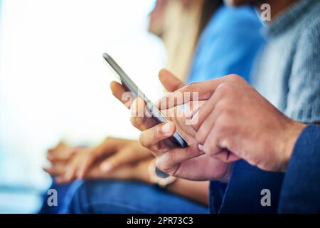 Modern technology is the new trend. Cropped shot of unrecognizable businessman using a smartphone during a conference in a modern office. Stock Photo