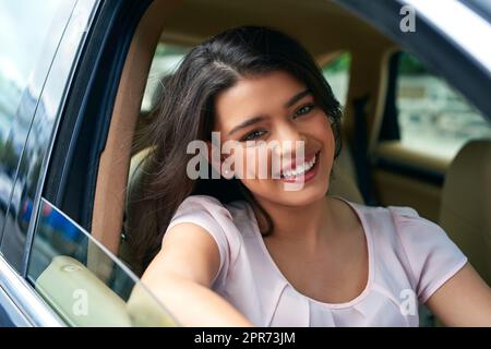She is a happy new car owner. Shot of an attractive young woman driving a car. Stock Photo