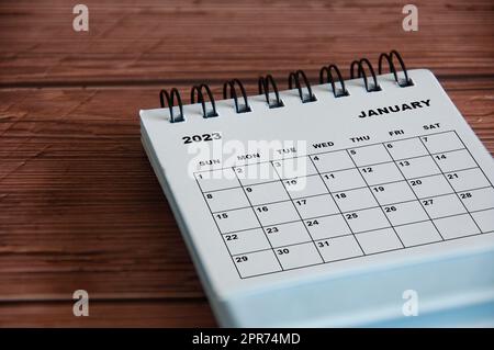 January 2023 white desk calendar on wooden table background. Calendar concept Stock Photo