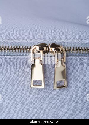 golden zippers with golden zippers are fastened on a blue leather object close-up Stock Photo