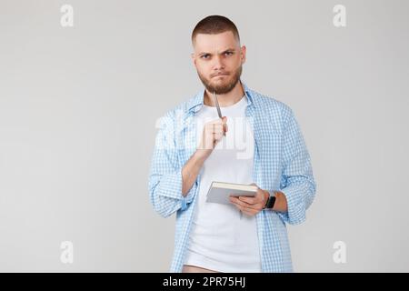 handsome man in blue shirt writing note in notebook Stock Photo