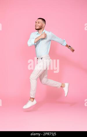man in summer clothes jumping on pink background. Stock Photo