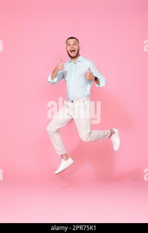 man in summer clothes jumping on pink background. Stock Photo