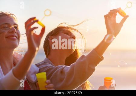 Blowing their cares away. Shot of a group of female friends using the breeze to blow bubbles. Stock Photo