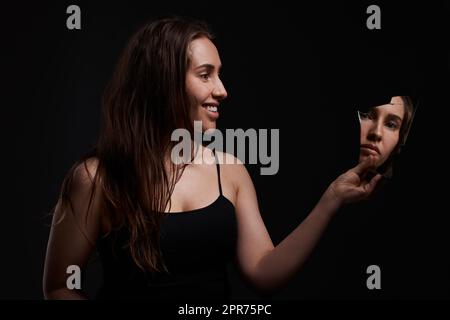 Youll never be in control. Shot of a creepy woman grinning at her reflection in a broken mirror. Stock Photo