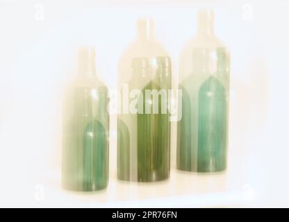 Artistic design of old glass bottles with blury motion effect, isolated on white background. Abstract blurred colorful light on three green glass bottles. Long exposure effect of dreamy drunk vision Stock Photo