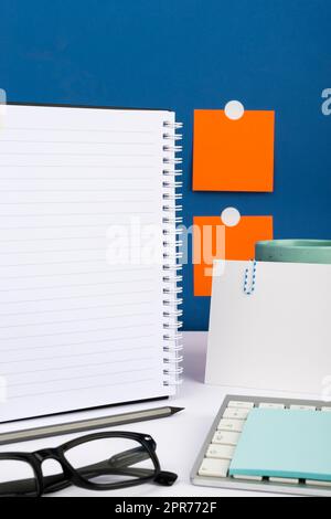 Important Message Written On Notebook On Desk With Pencil, Keyboard, Note And Glasses. Crutial Informations Presented On Notepad On Table With Memos On Wall. Stock Photo