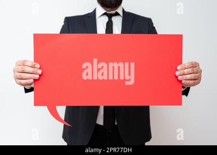 Businessman Holding Speech Bubble With Important Messages. Man In Suit Presenting Crutial Informations On Dialogue Balloon. Gentleman Showing Recent Updates On Paper. Stock Photo