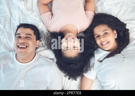 I put them over everything. Portrait of a beautiful young family talking and bonding in bed together. Stock Photo