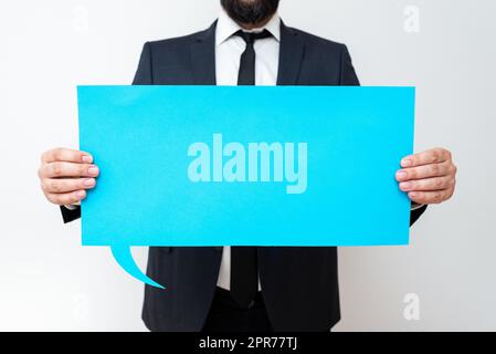 Businessman Holding Speech Bubble With Important Messages. Man In Suit Presenting Crutial Informations On Dialogue Balloon. Gentleman Showing Recent Updates On Paper. Stock Photo