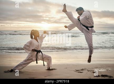 Karate all day. Shot of two young martial artists practicing karate on the beach. Stock Photo