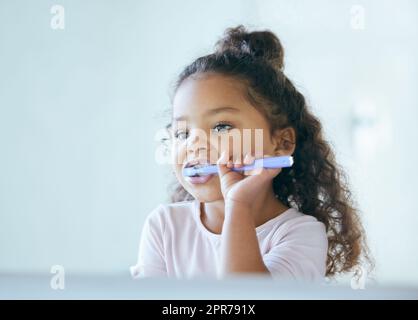 Getting minty fresh breath. Shot of a little girl brushing her teeth in a bathroom at home. Stock Photo