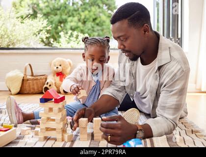 Lets build a house. a little girl playing with blocks with her father at home. Stock Photo