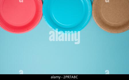 Empty paper disposable plates on a blue background, top view. Stock Photo