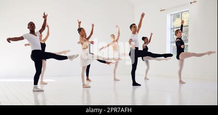 Dancing is the poetry of the foot. a group of ballet dancers practicing a routine in a dance studio. Stock Photo