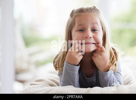 How far can my mouth stretch. a young girl making funny faces at home. Stock Photo