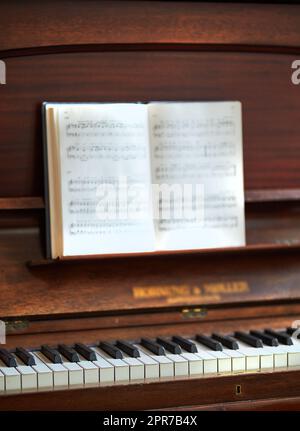 Closeup of a vintage piano and keyboard with a sheet music book. An empty antique or wooden musical instrument for playing classical jazz or used for old traditional songwriting and rehearsals Stock Photo
