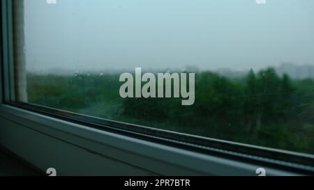 Raindrops on the window pane. Blurred background outside the window in the rain. Stock Photo