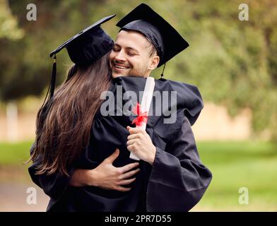I am so proud of us. Shot of a young man hugging her friend on graduation day. Stock Photo